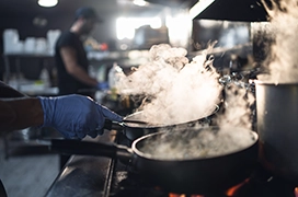 A closeup of line cooks cooking in a restaurant kitchen.