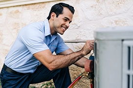 Aire Serv tech kneeling next to HVAC system.