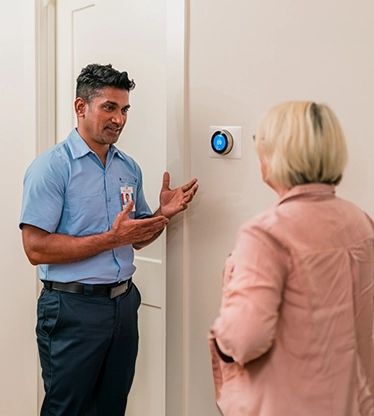 Aire Serv tech showing customer thermostat.