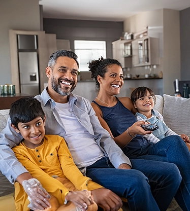Smiling family sitting together on sofa.