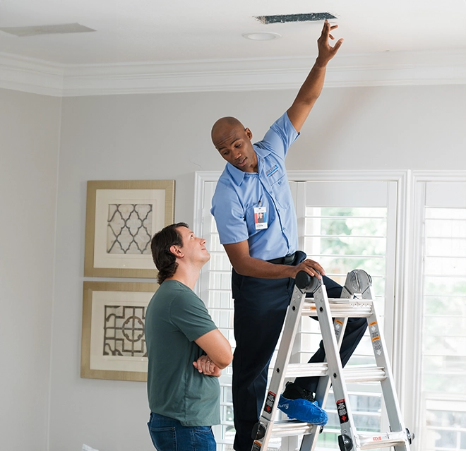 A technician showing a ceiling vent to the client.