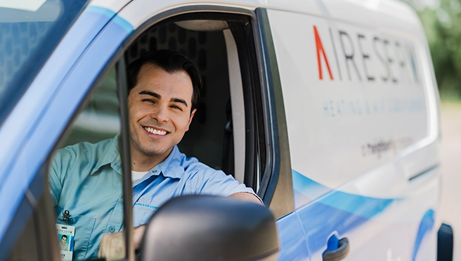 An asv technician smiling in a van.