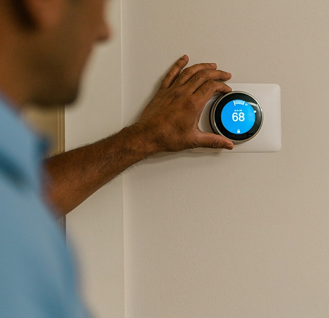 ASV technician adjusting the thermostat on the wall.
