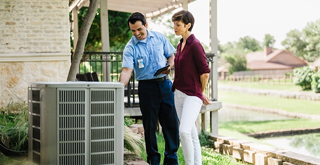 AireServ technician looks at an air conditioning unit with a customer.