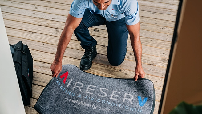 Aire Serv technician placing mat.