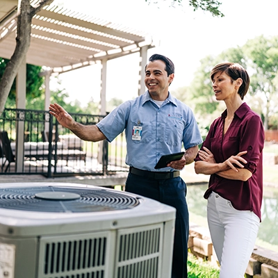Aire Serv tech explaining HVAC system to female customer.