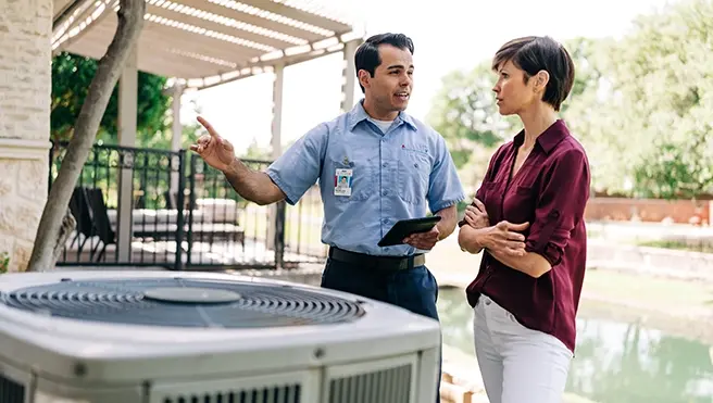 Aire Serv technician talking with a client in front of an air conditioning unit.
