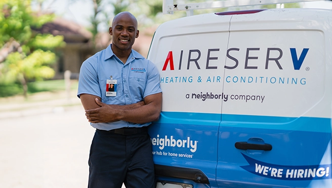 Aire Serv smiling tech standing with arms folded in back of branded van.