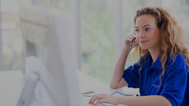 Customer service rep sits at a desk speaking to a customer.