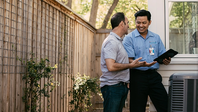An Aire Serv technician talking with a customer outside their home.