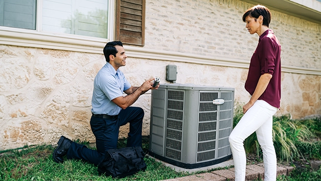 An Aire Serv technician talking with a customer around their air conditioning unit.