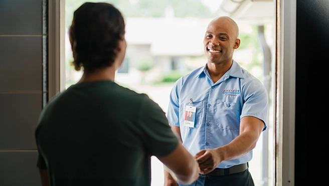 An Air Serv technician greets a customer at their front door.