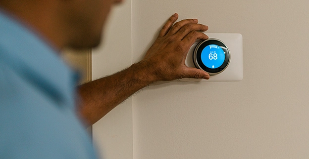 Aire Serv technician adjusting a customer's thermostat.