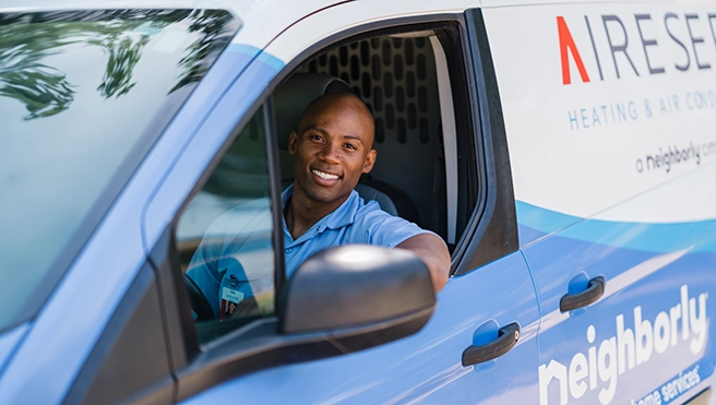 Aire Serv technician sitting in the driver's seat of an Aire Serv van.