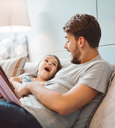 Father and daughter happy sitting on couch.