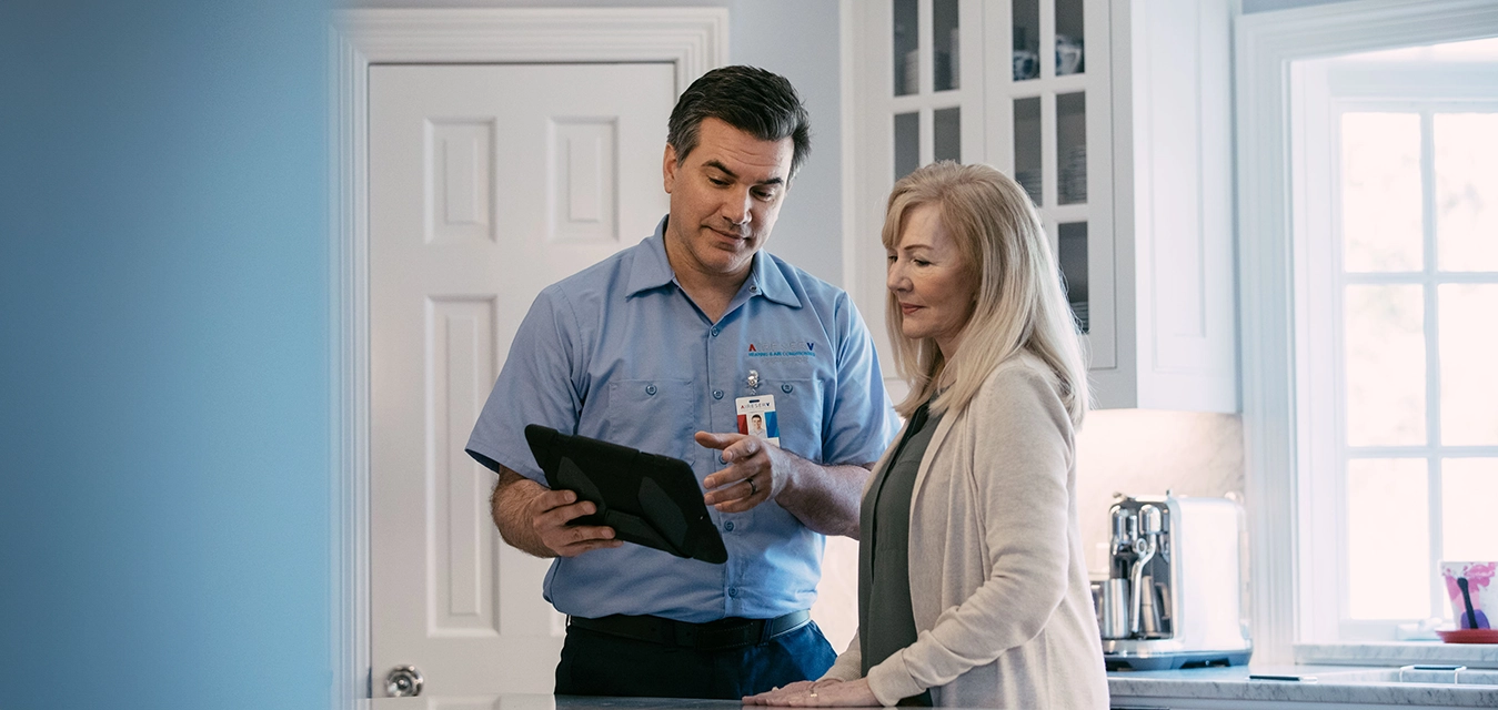 Aire Serv tech explaining service to female customer using a tablet.