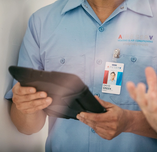 A closeup of an Aire Serv technician holding a tablet device.