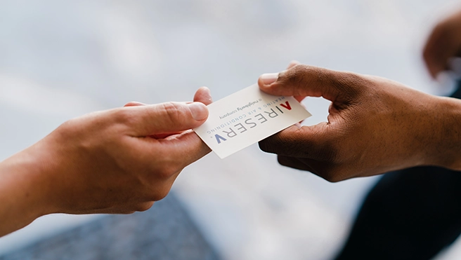 Aire Serv technician handing over a business card to a customer.