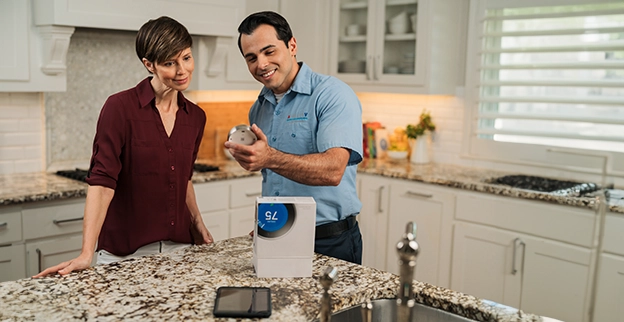Aire Serv technician showing a customer a new thermostat before installation.