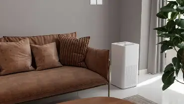 An air purifier is seen next to a couch in a modern living room. 