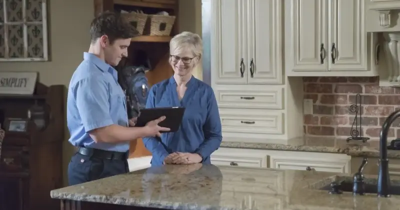 Air conditioning repairman speaking with a customer in their home.