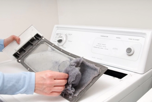 A man removes built-up lint and dust from his dryer&rsquo;s lint filter. | Aire Serv of Western North Carolina