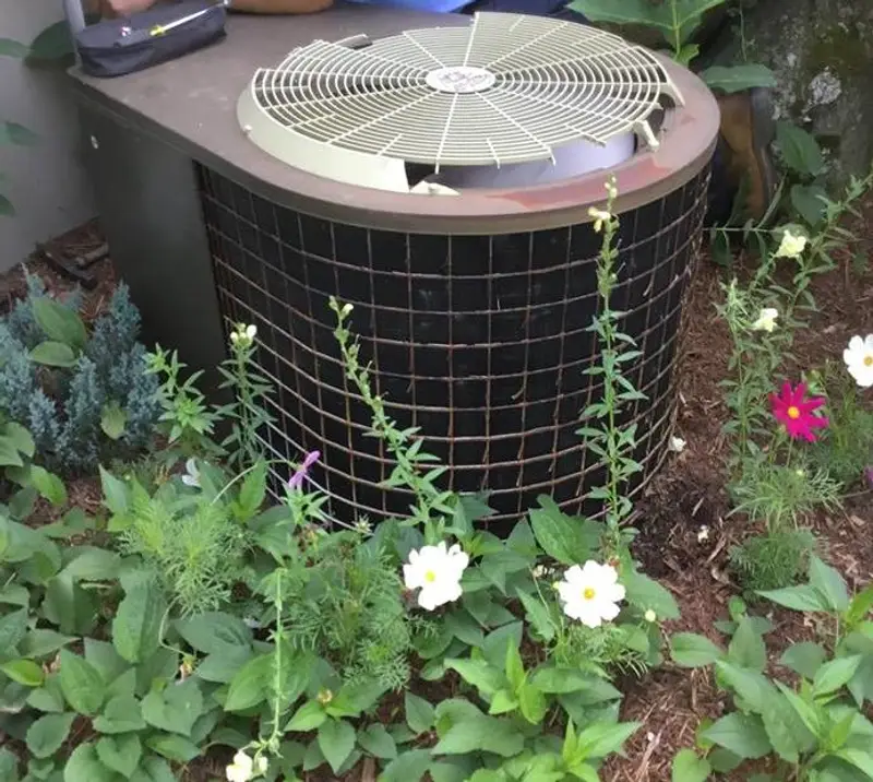air conditioning unit outside surrounded by plants
