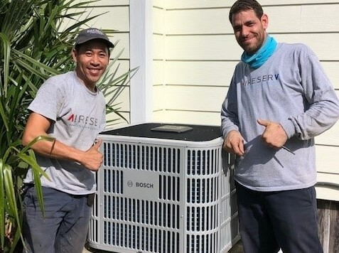 Aire Serv team standing by an air purification unit.