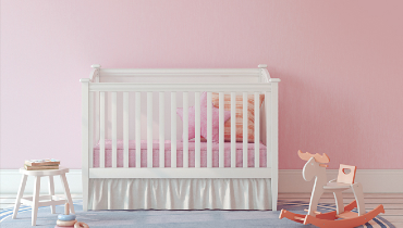 Baby's room with crib, stool, rocking horse, and pink walls