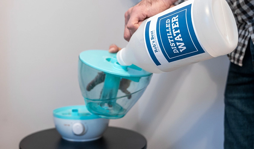 Man pouring distilled water into humidifier