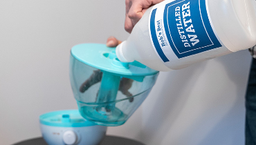 Man pouring distilled water into humidifier.