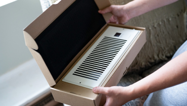 Person opening box containing a new duct vent