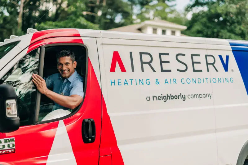 Aire Serv service professional smiling welcomingly in driver's seat of Aire Serv van.