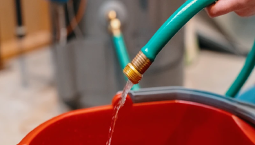 Hose filling up bucket with water.