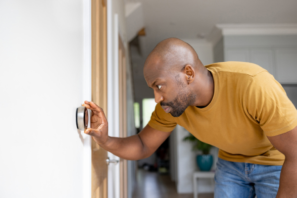 A man adjusts his smart thermostat in his home. | Aire Serv&reg; of North Central Arizona.