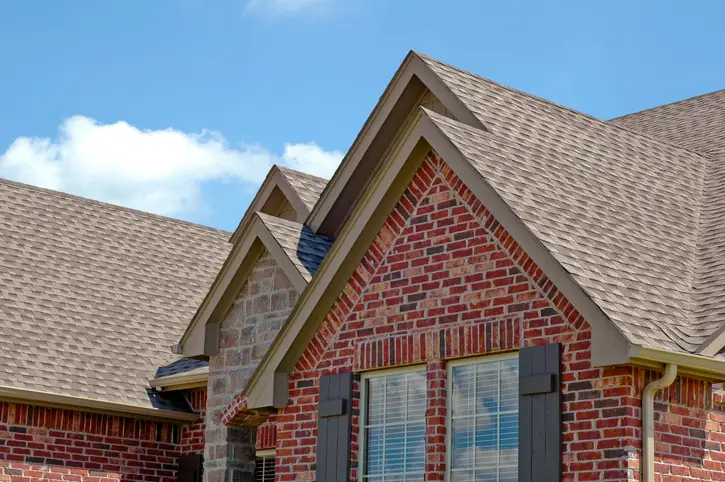 A close-up view of a modern brick house with a shingled roof on a sunny day. | Aire Serv&reg; of Jackson