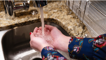 Woman washing her hands in kitchen sink