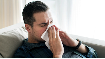 Man wiping his nose with tissue