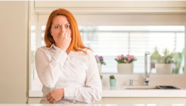Woman plugging her nose because of a musty smell in her house