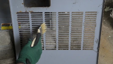 Technician cleaning front cover a furnace before reinstalling