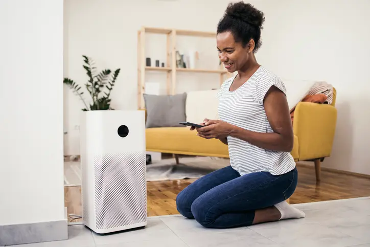 A woman sets up an air purifier with her mobile phone. | Aire Serv&reg; of North Central Arizona