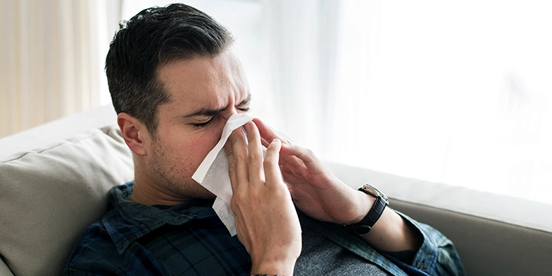 Man wiping his nose with tissue