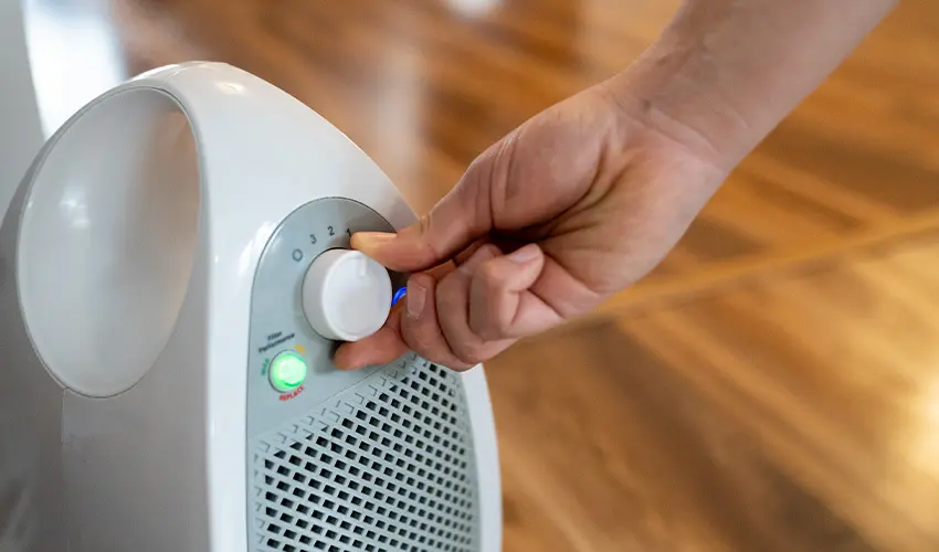 Person turning air purifier knob.